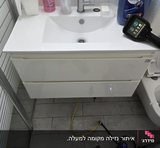 כיור עם ברז, צינור צהוב ומכשיר מדידה